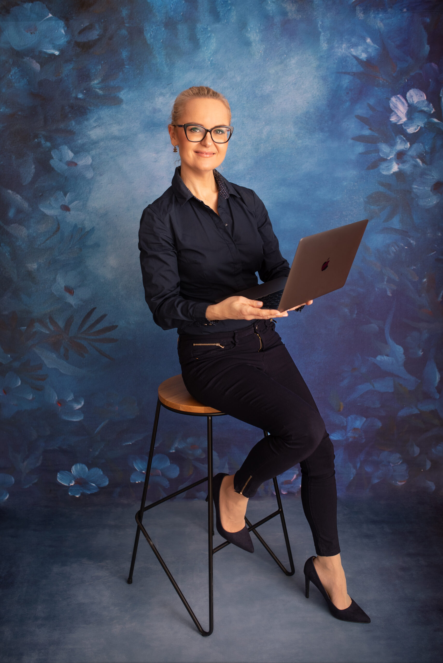 Pani Tamara siedząca na krześle, uśmiechnięta, trzyma w rękach laptopa